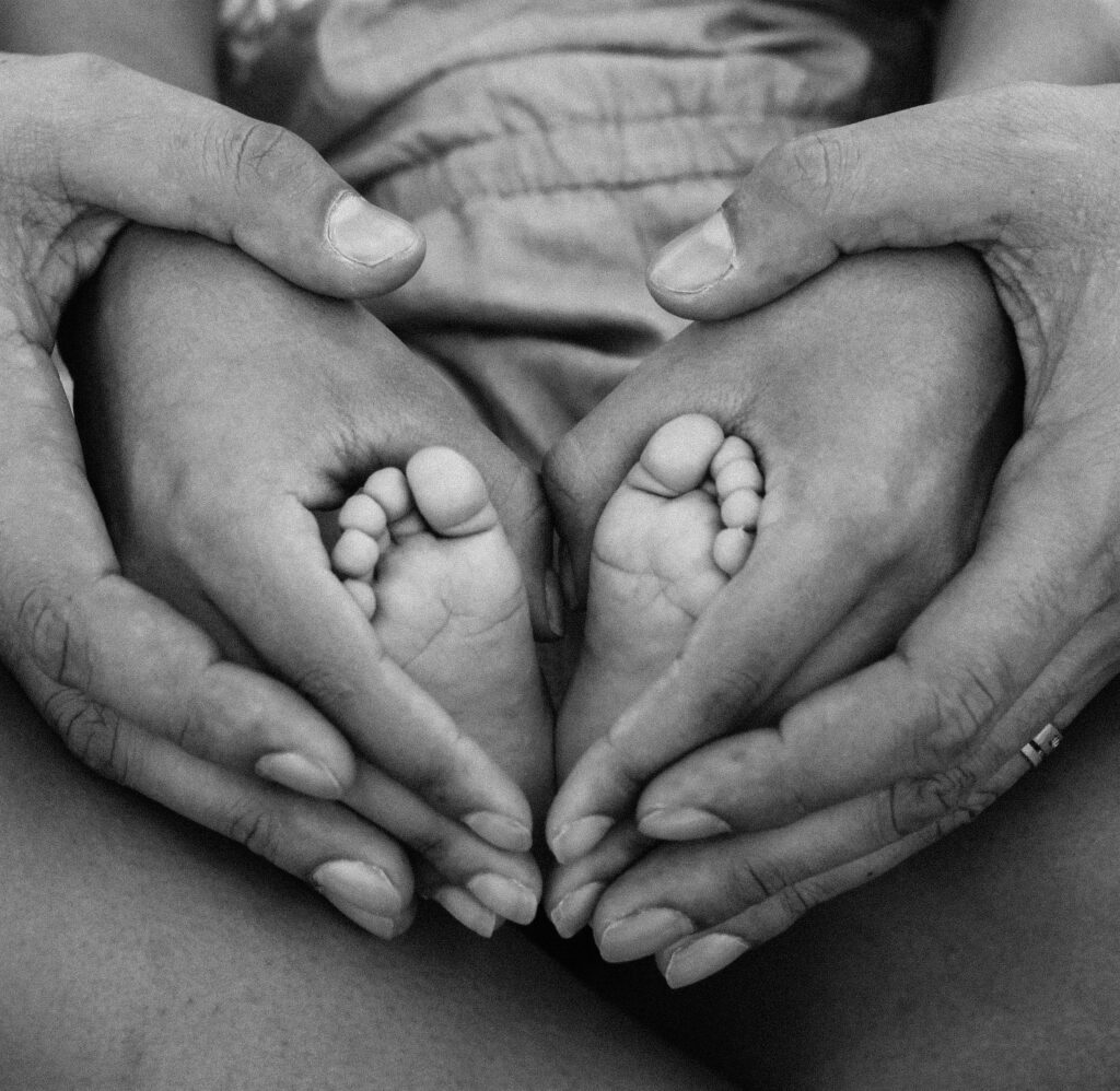 A couple holding the feet of a new born baby used to represent a postpartum doula service